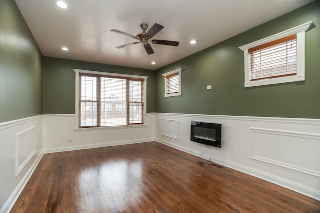 unfurnished living room featuring a glass covered fireplace, dark wood-type flooring, and wainscoting