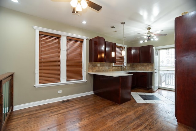 kitchen featuring visible vents, decorative backsplash, dark wood-type flooring, light countertops, and a sink