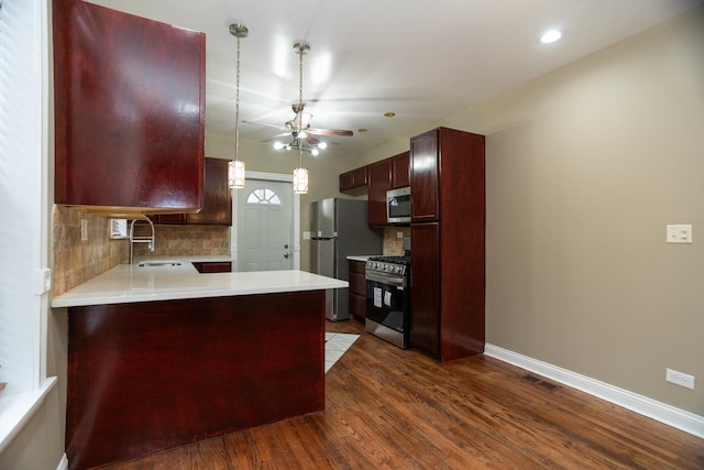 kitchen featuring dark wood-style floors, a sink, stainless steel appliances, light countertops, and backsplash