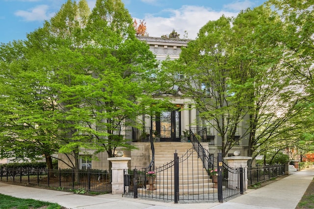 view of front facade with stone siding, a fenced front yard, and a gate