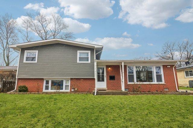 split level home with brick siding and a front lawn