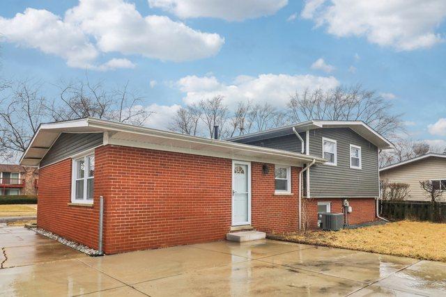 tri-level home with central AC and brick siding