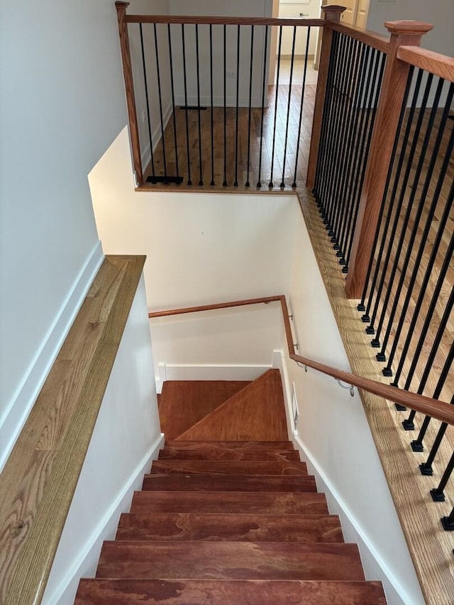 stairway with baseboards and wood finished floors