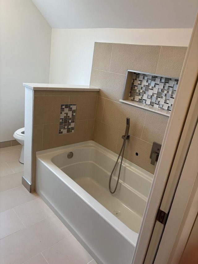 full bathroom featuring tile patterned flooring, toilet, and a bath