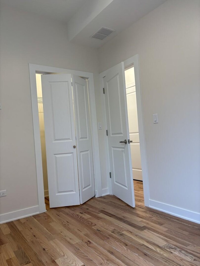 unfurnished bedroom featuring a closet, baseboards, light wood-style floors, and visible vents