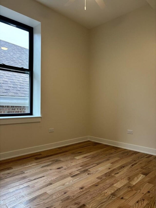 empty room with baseboards, wood finished floors, and a ceiling fan