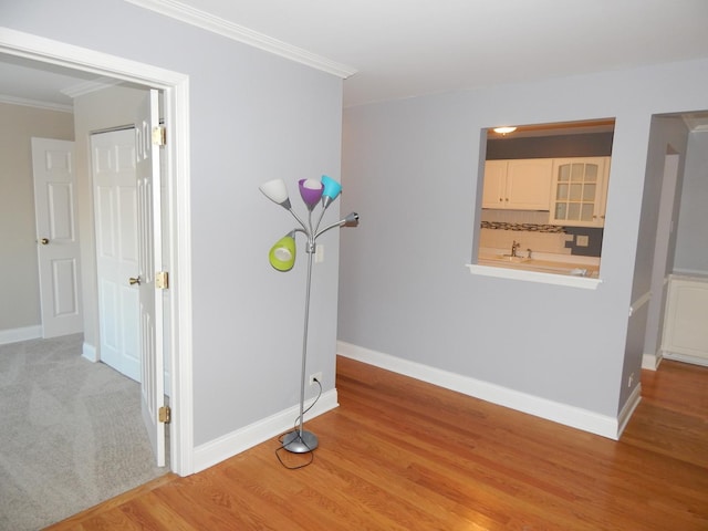 interior space with crown molding, light wood-type flooring, and baseboards