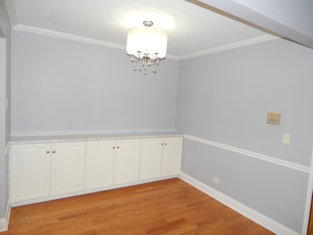 unfurnished dining area featuring baseboards, a chandelier, ornamental molding, and light wood finished floors