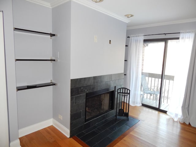 unfurnished living room with baseboards, wood finished floors, a tile fireplace, and ornamental molding