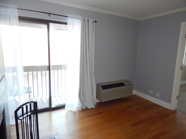 interior space featuring baseboards, heating unit, wood finished floors, and crown molding