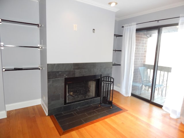 living room featuring a fireplace with flush hearth, ornamental molding, baseboards, and wood finished floors