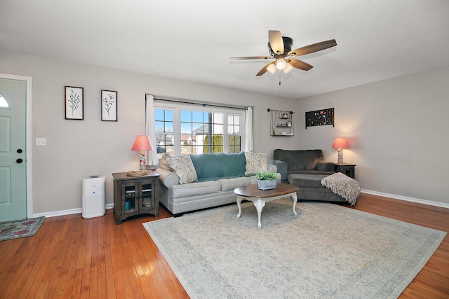 living room featuring wood-type flooring, a ceiling fan, and baseboards