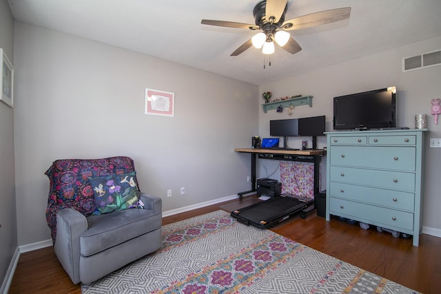 living area with baseboards, visible vents, and wood finished floors