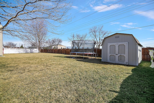 view of yard featuring a shed, a trampoline, a fenced backyard, and an outbuilding