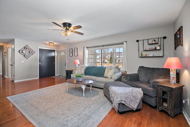 living room with a ceiling fan, baseboards, and wood finished floors