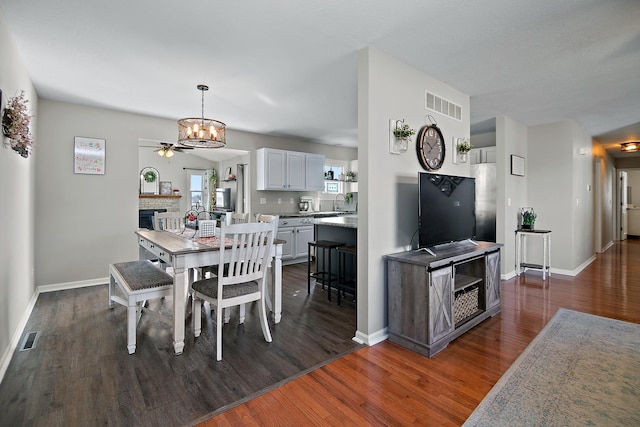 dining room with dark wood-style flooring, a fireplace, and visible vents