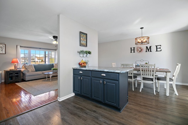 kitchen with ceiling fan with notable chandelier, baseboards, hanging light fixtures, blue cabinetry, and dark wood finished floors