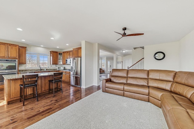 living area with recessed lighting, dark wood-type flooring, a ceiling fan, baseboards, and stairway