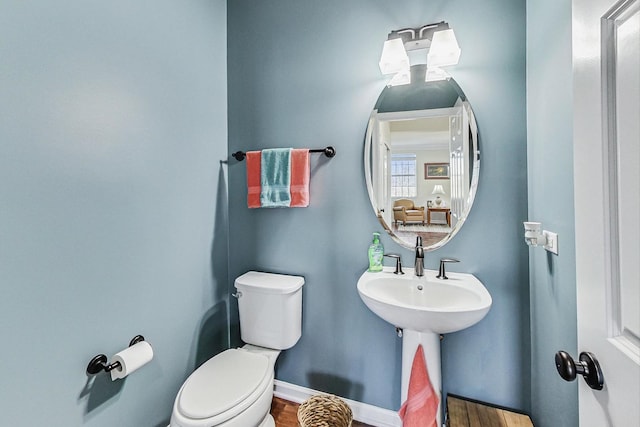 half bathroom featuring toilet, baseboards, and wood finished floors