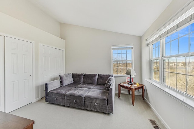 carpeted living room featuring lofted ceiling, baseboards, and visible vents