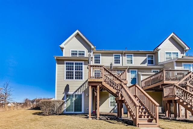 back of house featuring stairway, a deck, and a lawn