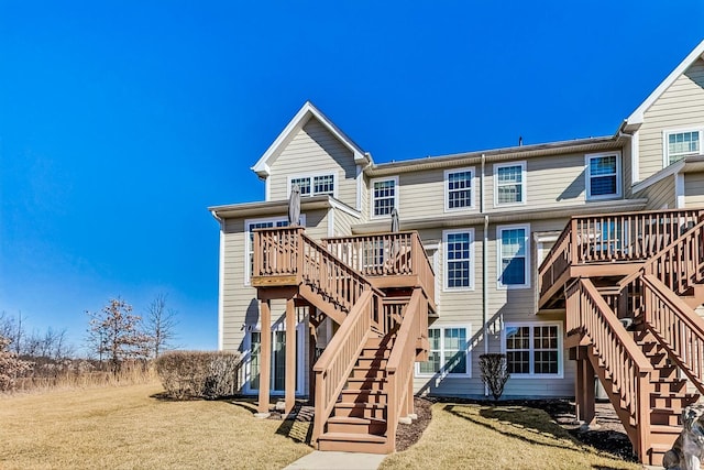 back of property featuring a deck, a yard, and stairway