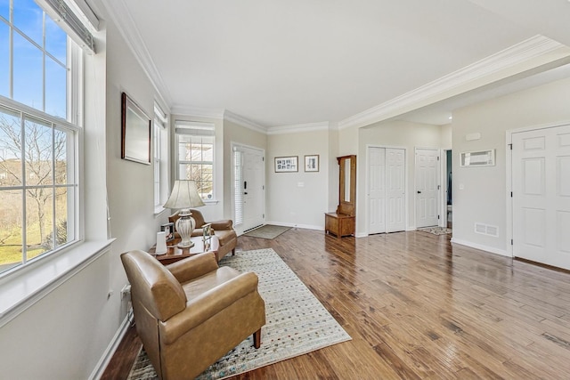 foyer entrance with plenty of natural light, wood finished floors, visible vents, and crown molding