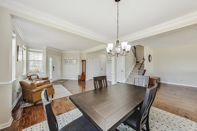 dining room with an inviting chandelier, wood-type flooring, stairway, and crown molding