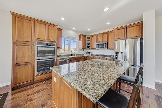 kitchen with appliances with stainless steel finishes, brown cabinets, and light stone countertops