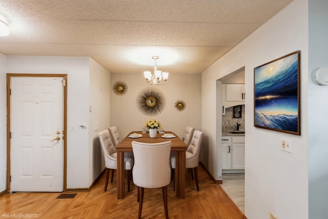 dining area with parquet floors, a notable chandelier, visible vents, a textured ceiling, and baseboards