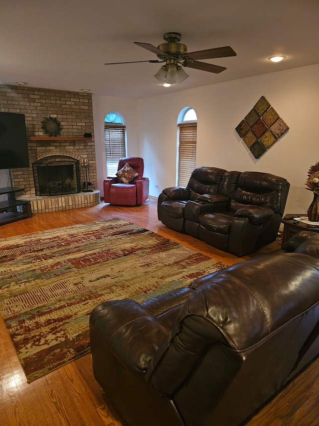 living area with ceiling fan, a fireplace, and wood finished floors