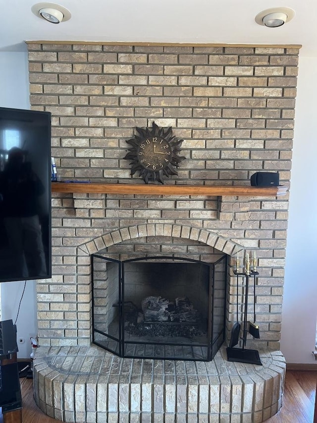 interior details with a brick fireplace, baseboards, and wood finished floors