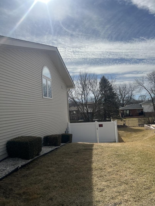 view of side of property with a gate, fence, and a yard