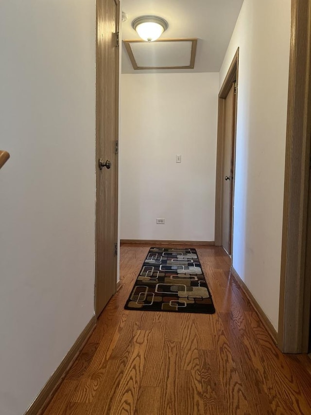 corridor with attic access, baseboards, and wood finished floors