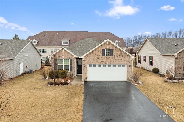 traditional home featuring aphalt driveway, brick siding, a shingled roof, a front yard, and a garage