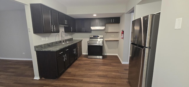 kitchen with under cabinet range hood, appliances with stainless steel finishes, dark wood finished floors, and a sink