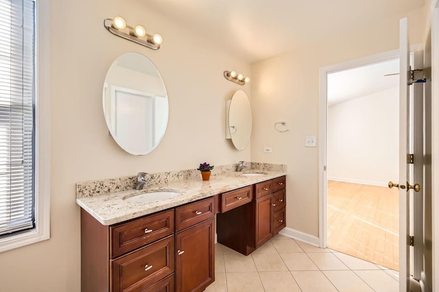 full bathroom with double vanity, baseboards, a sink, and tile patterned floors