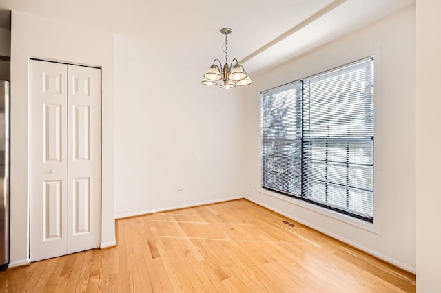 unfurnished room with light wood finished floors, baseboards, and a chandelier