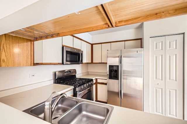 kitchen with wooden ceiling, stainless steel appliances, a sink, white cabinetry, and light countertops