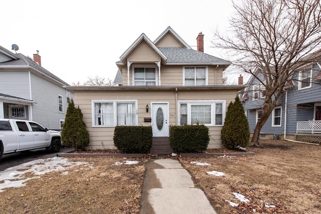 view of front of home with a shingled roof and a chimney