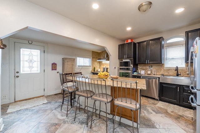 kitchen with plenty of natural light, stainless steel appliances, a sink, and a kitchen breakfast bar