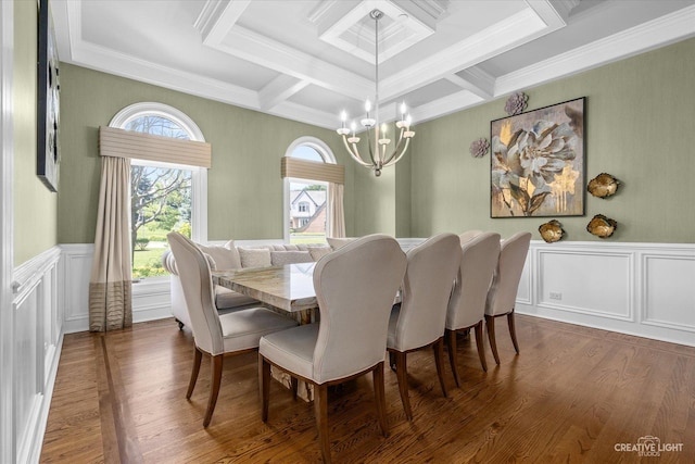 dining space featuring wainscoting, ornamental molding, wood finished floors, a decorative wall, and a notable chandelier