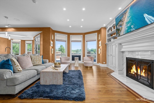 living area featuring baseboards, a fireplace, wood finished floors, and recessed lighting