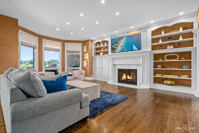 living room featuring a premium fireplace, built in features, wood finished floors, and recessed lighting