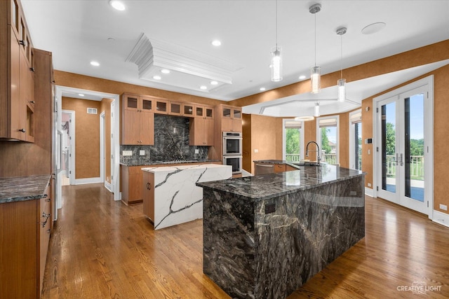 kitchen featuring brown cabinetry, a spacious island, stainless steel appliances, french doors, and a sink