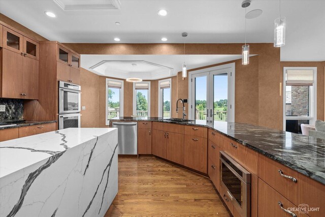 kitchen with light wood-style flooring, appliances with stainless steel finishes, brown cabinets, french doors, and a sink