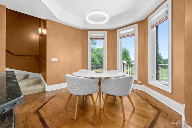 dining space featuring a tray ceiling, crown molding, stairway, and baseboards