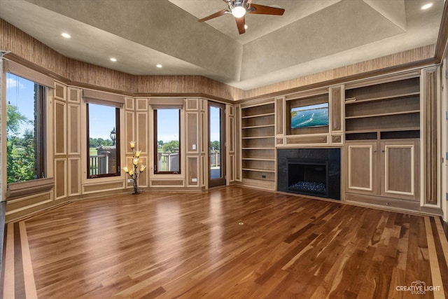 unfurnished living room featuring recessed lighting, a towering ceiling, a premium fireplace, ceiling fan, and wood finished floors