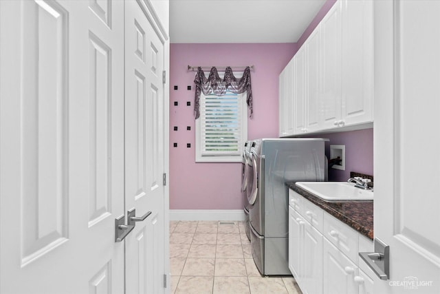 washroom with cabinet space, baseboards, a sink, and independent washer and dryer