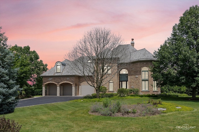 french country home with aphalt driveway, a front lawn, and a high end roof